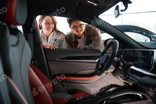Visualização: Mulher e homem olhando para dentro do carro escolhendo automóvel na concessionária