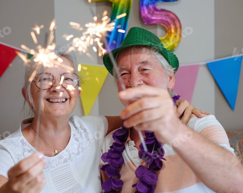 Preview: Cheerful senior couple celebrating 75th birthday with sparkles, a moment of joy together
