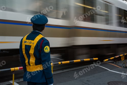 Preview: Back view of a man in uniform standing beside a moving train