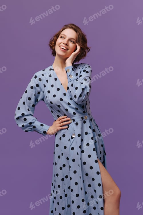 Preview: Young lady dreaming isolated over purple background. Charming stylish ginger in blue polka dot dres