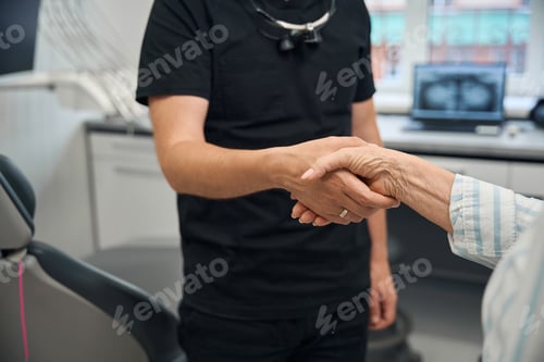 Preview: Doctor greets elderly lady at reception with handshake