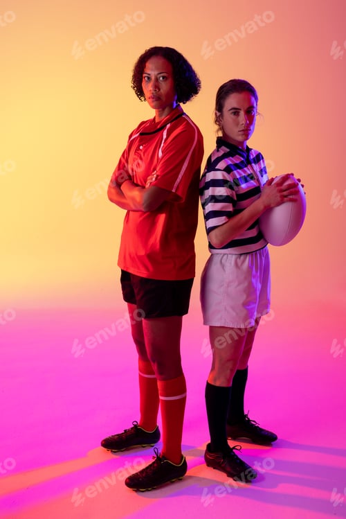 Preview: Portrait of two diverse female rugby players with rugby ball over neon pink lighting