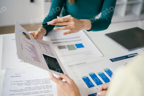 Preview: Two people are looking at a bunch of papers with graphs on them