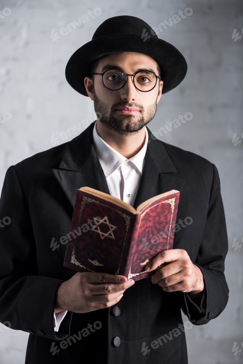 Preview: handsome and young jewish man in glasses holding tanakh