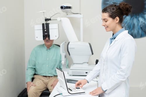 Preview: Happy young female ophthalmologist in whitecoat using eyesight testing equipment