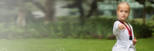 Preview: Little Caucasian girl with blonde hair six years exercising taekwondo outdoor web banner copy space