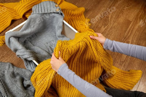 Preview: A young woman neatly puts stacks of clothes into a metal laundry basket.