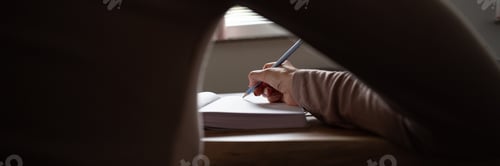 Preview: Under the arm view of a woman writing in notebook