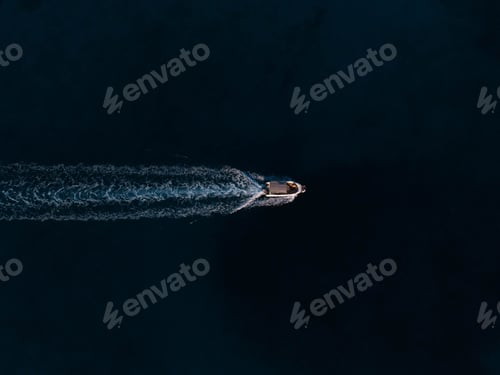 Preview: Aerial top view of a boat sailing in the water leaving a trail
