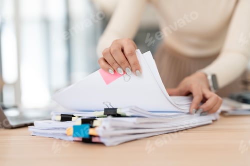 Preview: Businesswoman hands working in Stacks of paper files for searching and checking unfinished document