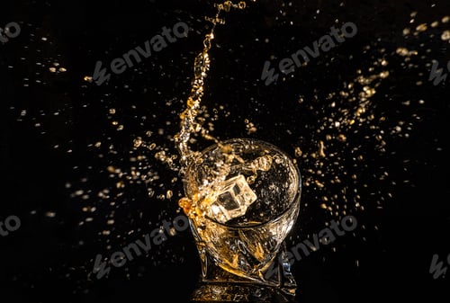 Preview: A glass of whiskey with splashes from the ice cube over black background.