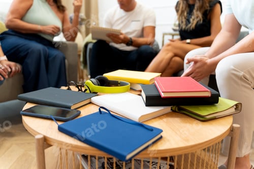 Preview: Diverse books and devices on coffee table during group discussion