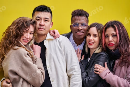 Preview: Multiracial young people having fun on yellow background. Group of friends of various ethnicities.