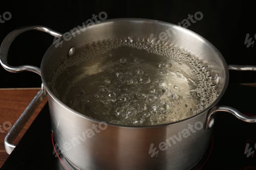 Preview: Metal pot with boiling water on stove in kitchen, closeup