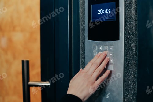 Preview: Woman hand press buttons on video intercom at entrance of apartment building in the night