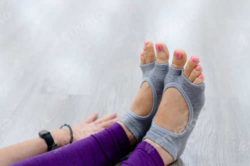 Preview: Close up Woman in purple leggings putting on her grey socks. Lady prepare for yoga workout.