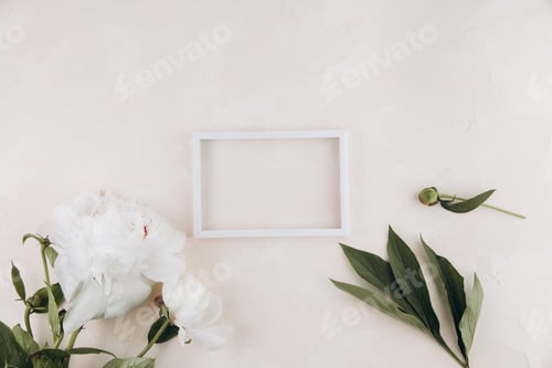 Preview: Pastel table with peony flowers and blank white frame with copy space