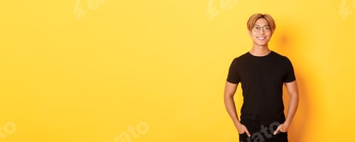 Preview: Handsome asian blond guy in glasses standing in black clothes and smiling pleased, yellow