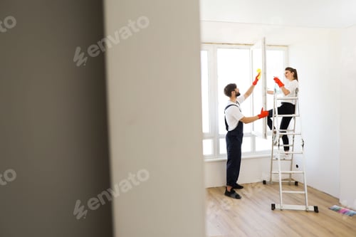 Preview: Beautiful caucasian couple wife and husband cleaning window together in room.