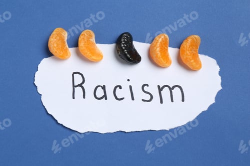 Preview: Card with word Racism and tangerine segments of different colors on blue background, top view