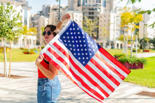 Preview: Selective focus of a woman waving an American flag during the US Independence Day on the 4th of July
