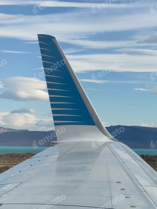 Preview: The tail of an airplane is seen in the distance, with a blue and white stripe