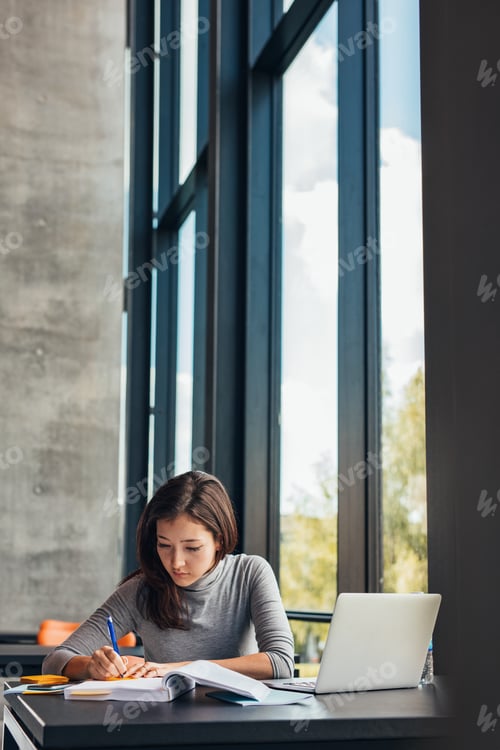 Preview: Student taking notes from books at library