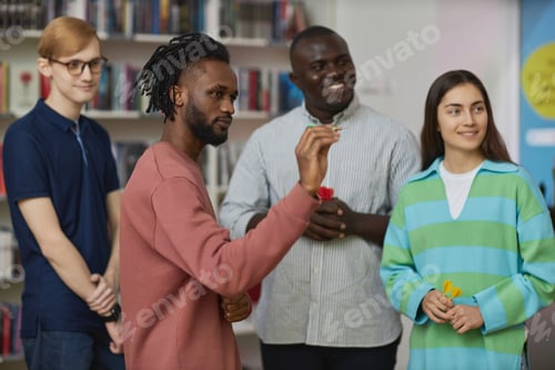 Preview: Young black man playing darts game indoors with group of people and aiming shot