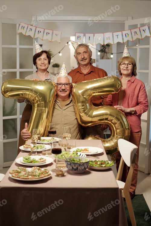 Preview: Happy senior people standing by aged man with inflatable numbers