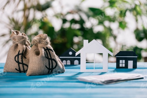 Preview: selective focus of paper houses and moneybags with dollar signs on wooden desk, mortgage concept