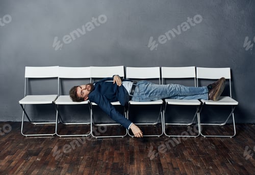 Preview: A man lies on chairs waiting for job interview manager