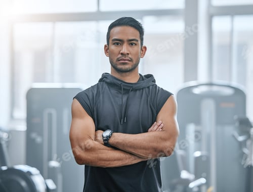 Preview: Portrait of one serious asian trainer alone in gym. Handsome focused coach standing with arms cross