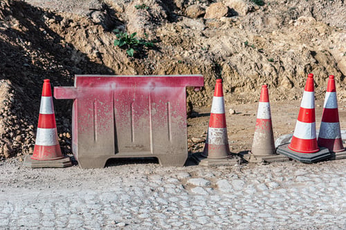 Preview: Multiple traffic cones placed on a road adjacent to a mound of sand