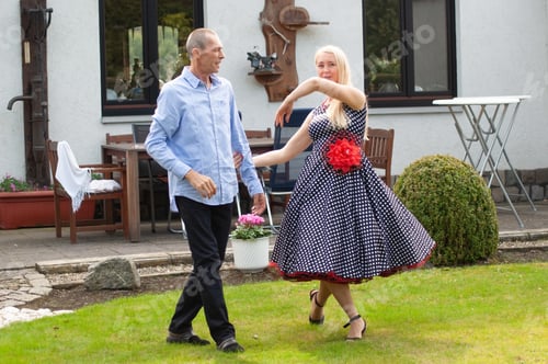 Preview: Happy middle aged couple man and woman dancing samba in the garden, people having fun