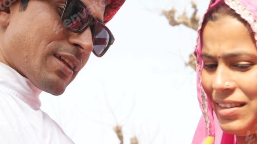 Preview: Closeup of an Indian couple in traditional outfits. The man wearing sunglasses.