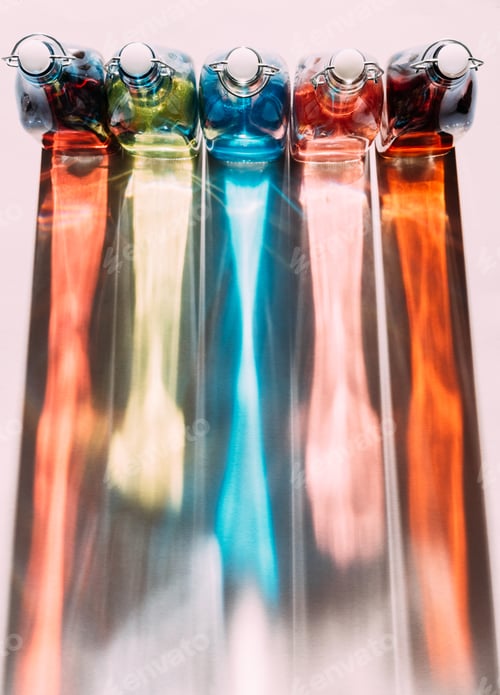 Preview: Top view shot of colorful glass bottles with flip top caps casting rainbow shadows on tabletop