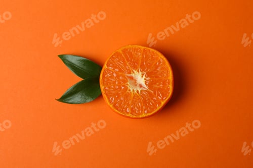 Preview: Half of mandarin with leaves on orange background