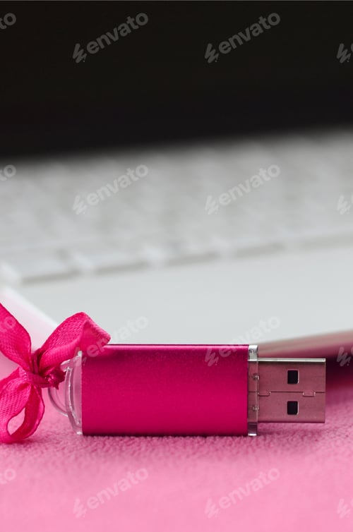Preview: Brilliant pink usb flash memory card with a pink bow lies on a blanket