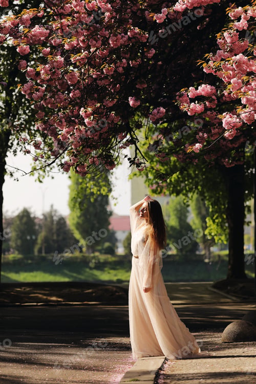Preview: girl among the cherry blossoms. girl walks around the city in the spring among the flowering trees