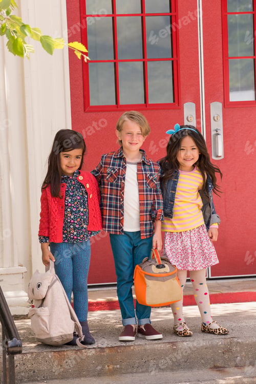 Preview: Portrait of elementary schoolboy and girls standing at elementary school doorway