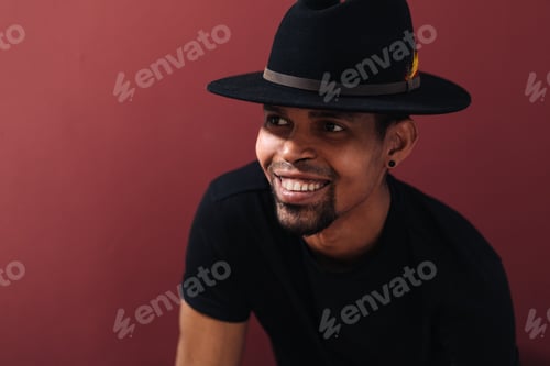 Preview: Smiling afro man portrait wearing black hat on burgundy background. Happy people concept