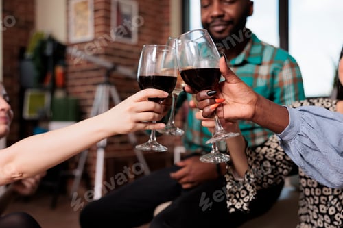 Preview: Diverse group of close friends at wine party clinking glasses while enjoying fun time together