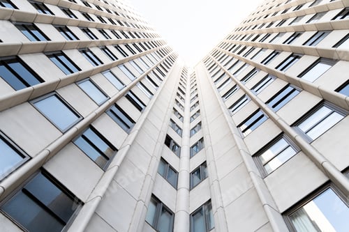 Preview: Very tall white building with glass windows seen from below