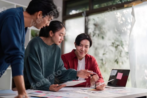 Preview: A team brainstorming ideas around a table filled with design resources.