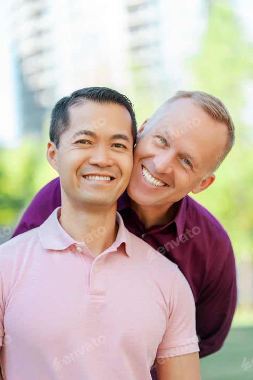 Preview: Portrait of smiling middle aged homosexual men hugging looking at camera on urban street