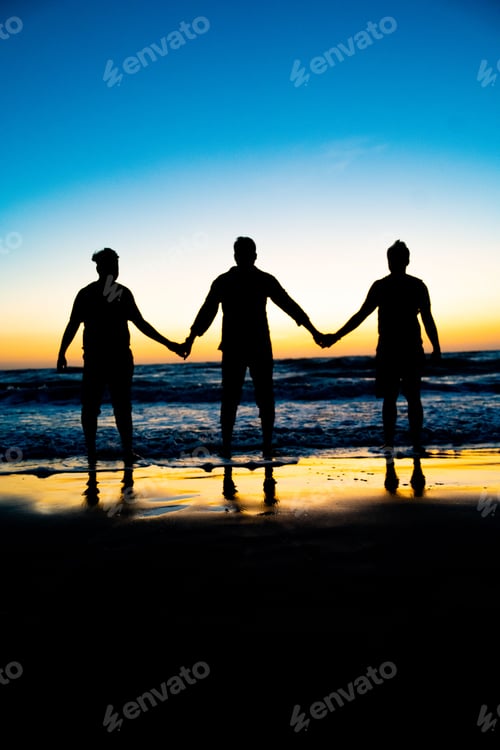 Preview: Three people standing with hands linked in a line at the beach on a sunny evening