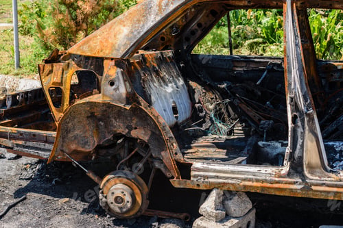 Preview: Burnt passenger car on the street of a dysfunctional area