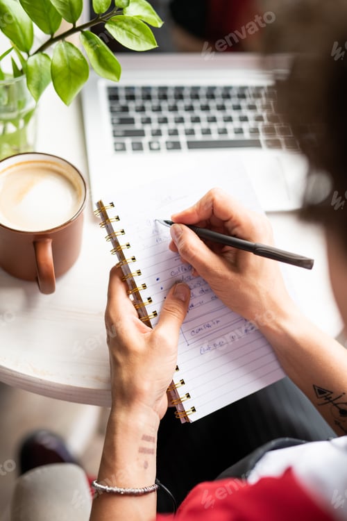 Preview: Young female manager making notes in notebook while organizing work