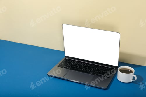 Preview: Open laptop with blank screen and cup of coffee on blue table
