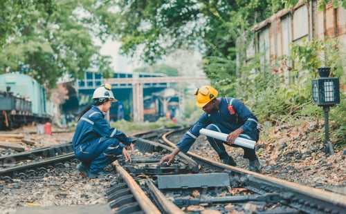 Preview: Engineer in safety gear inspects railway track for wear and alignment, ensuring safety standards.